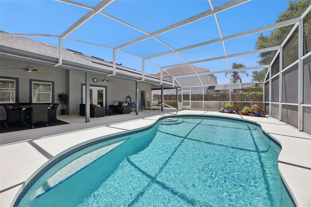 A screened-in patio features a swimming pool with steps and outdoor seating under a roof — 2948 PEMBRIDGE STREET, KISSIMMEE, FL