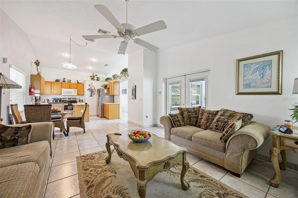 A living room with tile floors, a ceiling fan, and an open kitchen in back — 2948 PEMBRIDGE STREET, KISSIMMEE, FL
