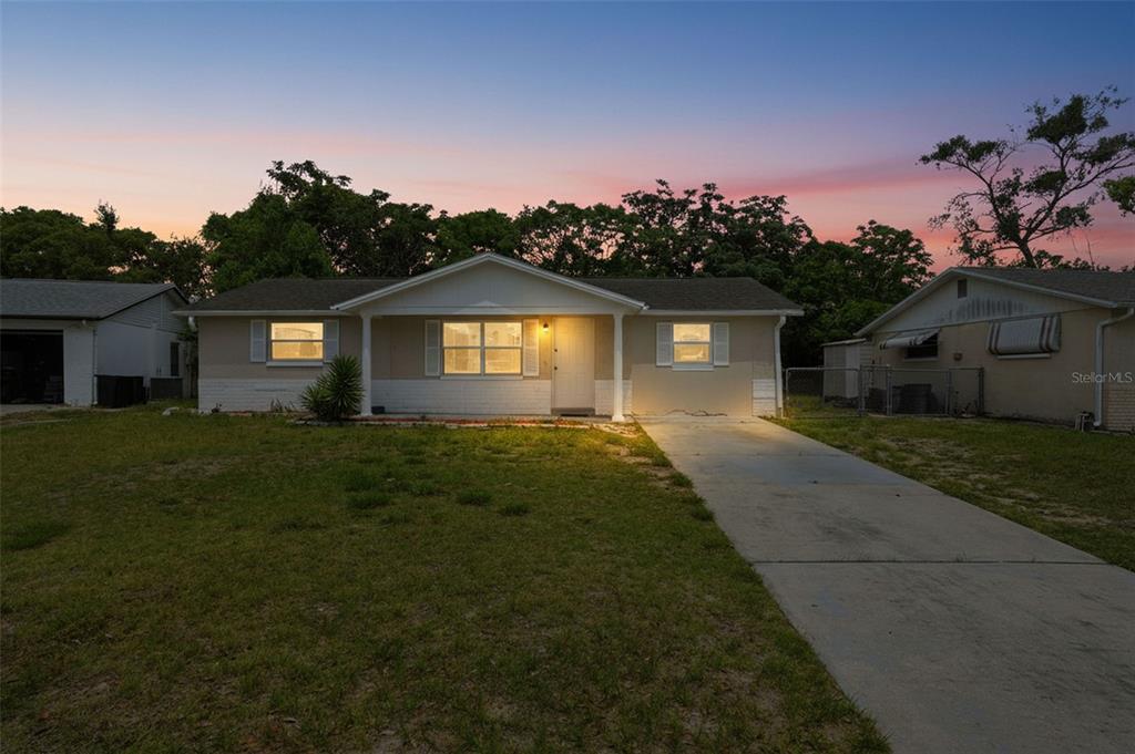 A single-story house with a white facade, a concrete driveway, and a grassy front yard — 11902 OCEANSIDE DRIVE, PORT RICHEY, FL