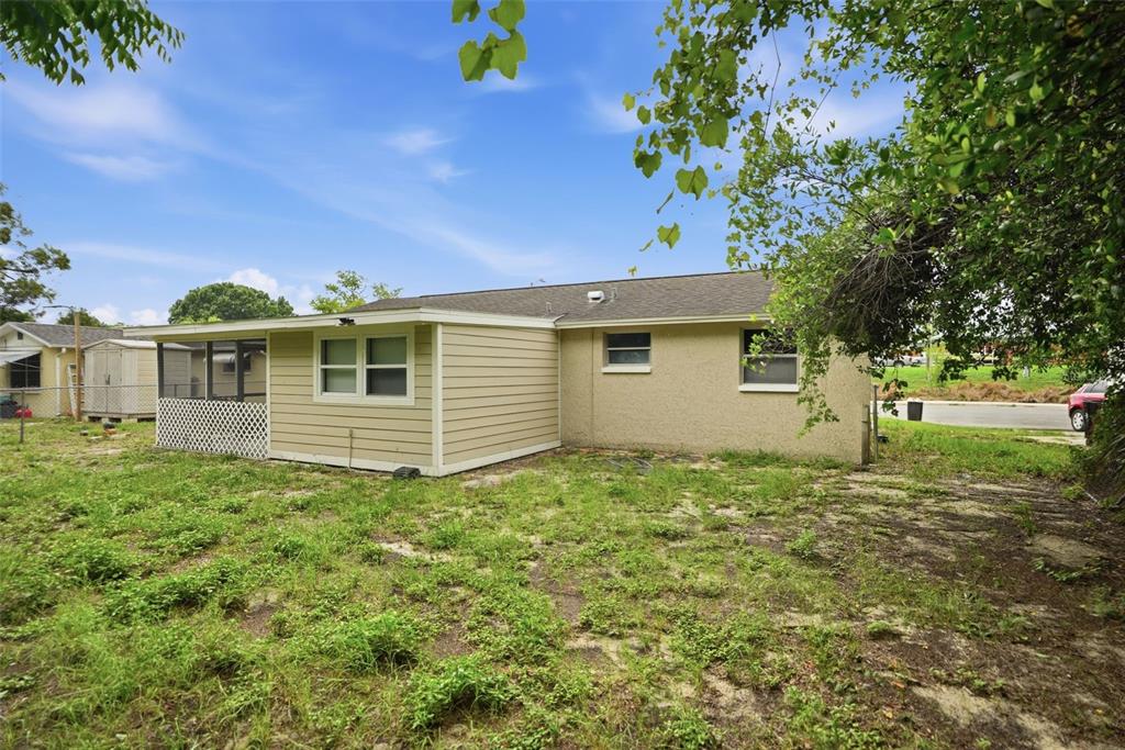 The exterior of a single-story house features tan siding, a screened porch, and a grassy yard — 11902 OCEANSIDE DRIVE, PORT RICHEY, FL