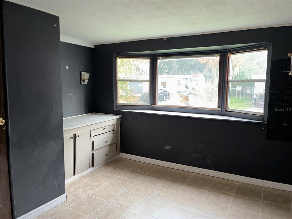 A room with black walls, tile flooring, a built-in cabinet, and a large bay window — 25 SUNSET CIRCLE, LAKE ALFRED, FL