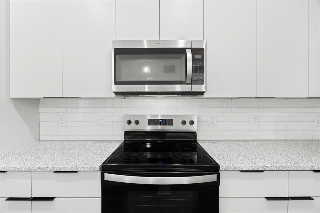 A kitchen features white cabinets, a stainless steel microwave, a black electric stove, and countertops — 1700 RANCH ROAD UNIT A2-6108, NOKOMIS, FL