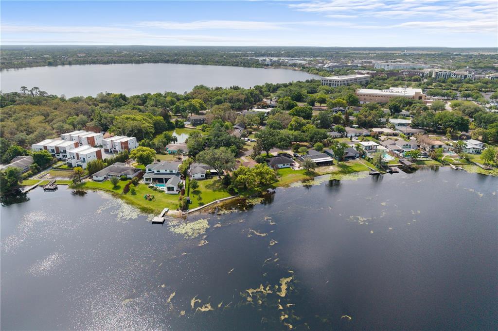 An aerial view shows waterfront homes and a modern townhouse complex beside a large lake — 1881 LAKE SPIER DRIVE, WINTER PARK, FL