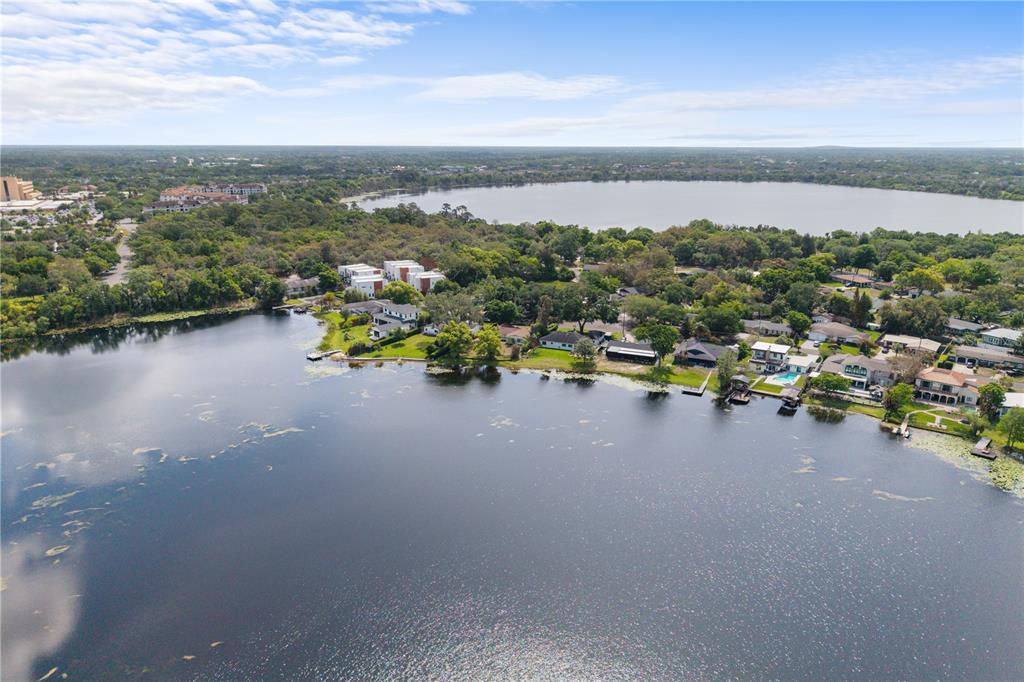 An aerial view shows houses along a lakefront with trees and a distant horizon — 1881 LAKE SPIER DRIVE, WINTER PARK, FL