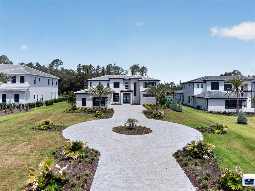 A modern two-story house features a circular paver driveway and landscaped front yard — 16044 PENDIO DRIVE, BELLA COLLINA, FL