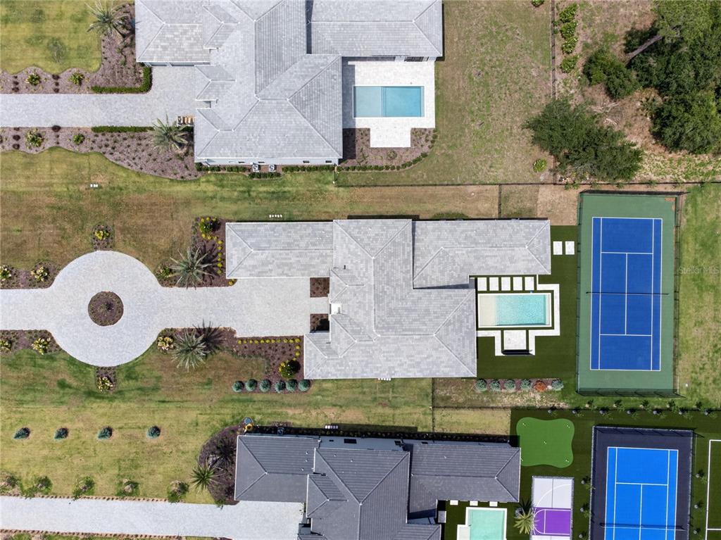 Aerial view of three residential properties featuring swimming pools, tennis courts, and landscaped grounds — 16044 PENDIO DRIVE, BELLA COLLINA, FL