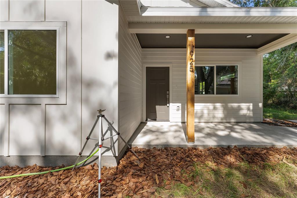 A modern house exterior features white siding, a covered porch, and a wooden support post — 925 NE 17TH DRIVE, GAINESVILLE, FL
