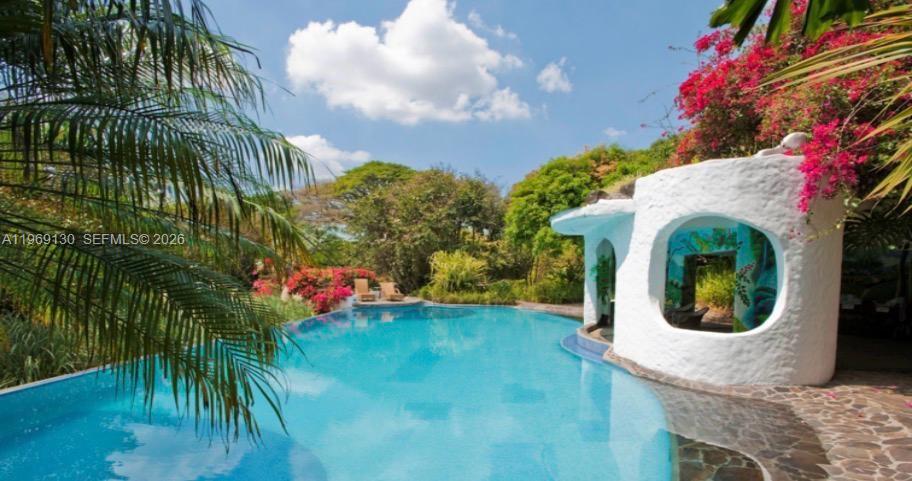 A swimming pool sits next to a white, rounded structure with a large arched opening — Santa Barbara de Heredia, Costa Rica, 00000, FL