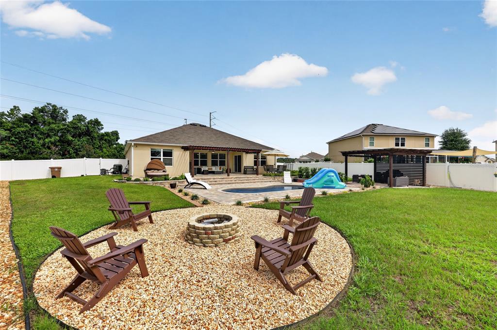 A backyard features a fire pit with Adirondack chairs, a swimming pool, and a patio — 4222 NE 29TH PLACE, OCALA, FL