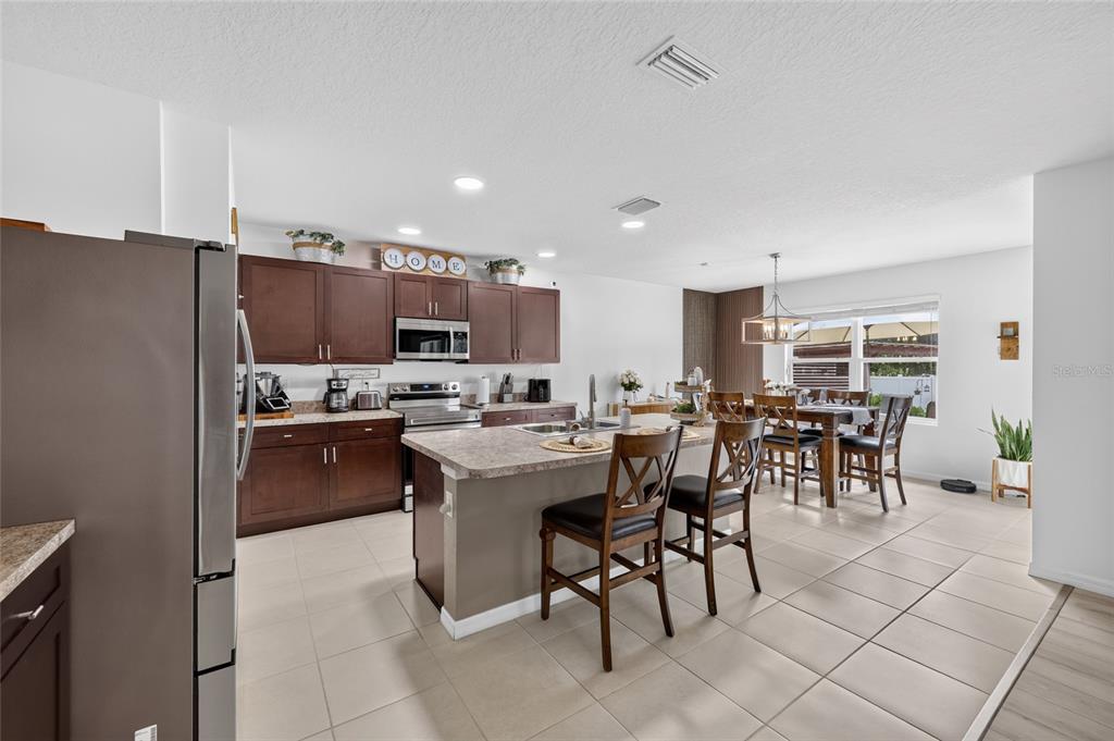 A kitchen with dark wood cabinets, a central island, and an adjacent dining area — 4222 NE 29TH PLACE, OCALA, FL