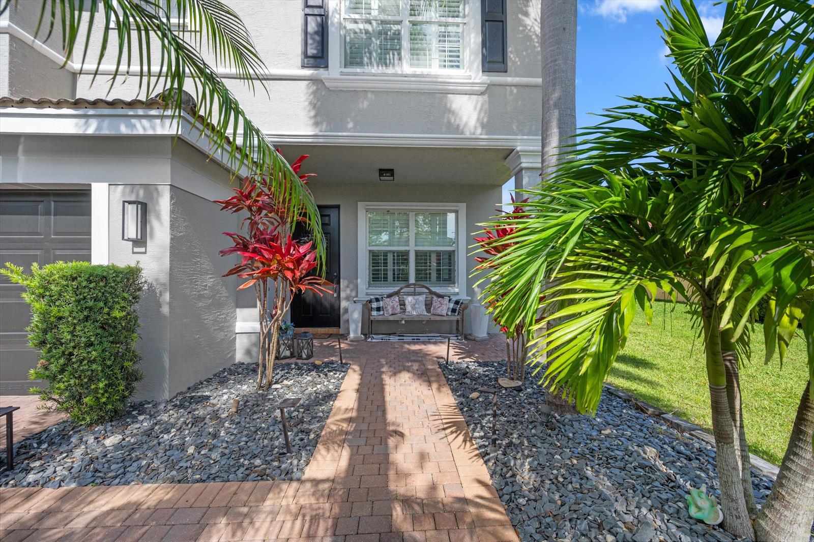 A brick walkway leads to the front entrance of a two-story house with landscaping — 11577 Ponywalk Trail, Boynton Beach FL 33473, BOYNTON BEACH, FL