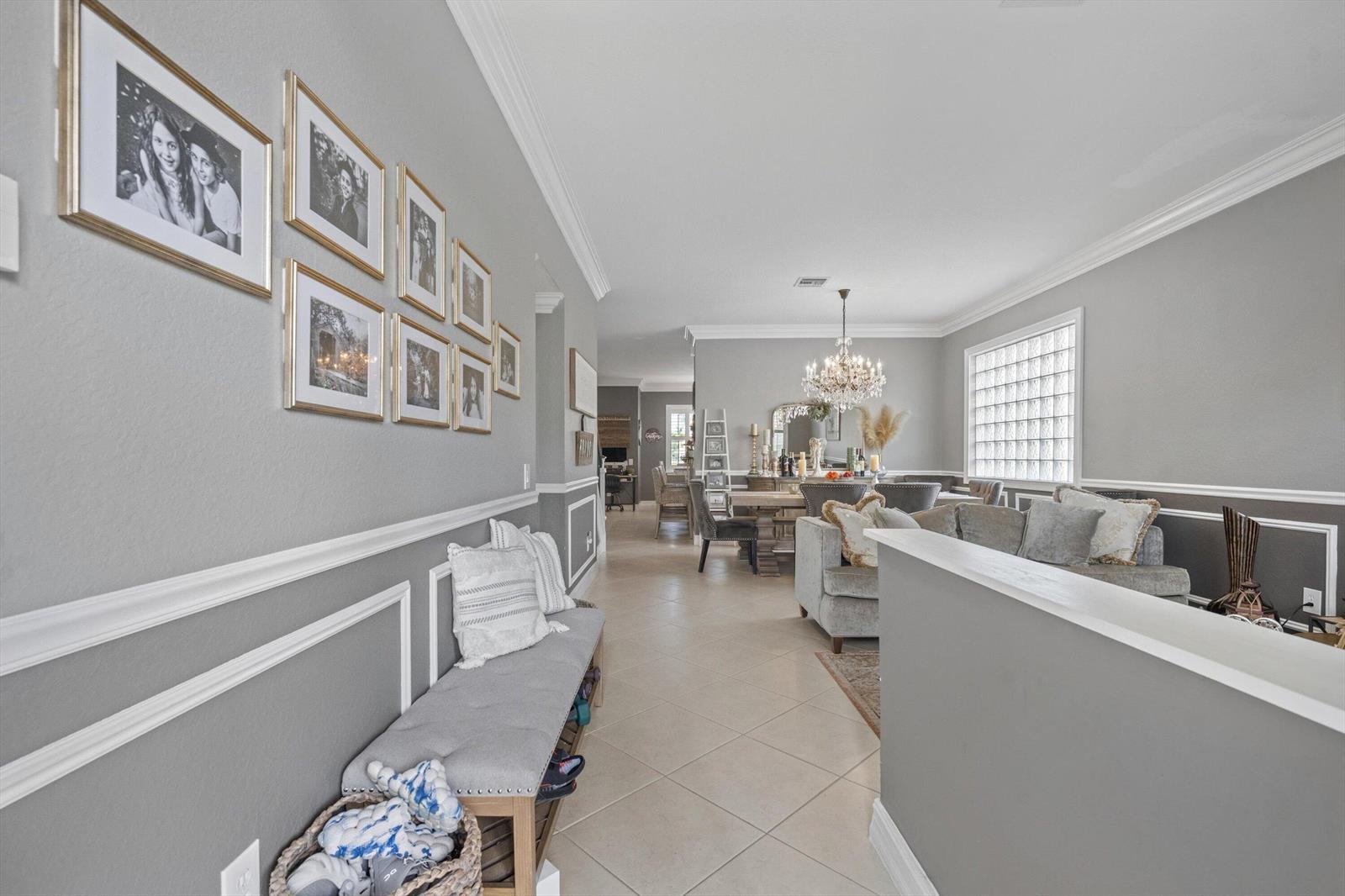 A hallway with a bench and gallery wall leads into a dining and living area — 11577 Ponywalk Trail, Boynton Beach FL 33473, BOYNTON BEACH, FL