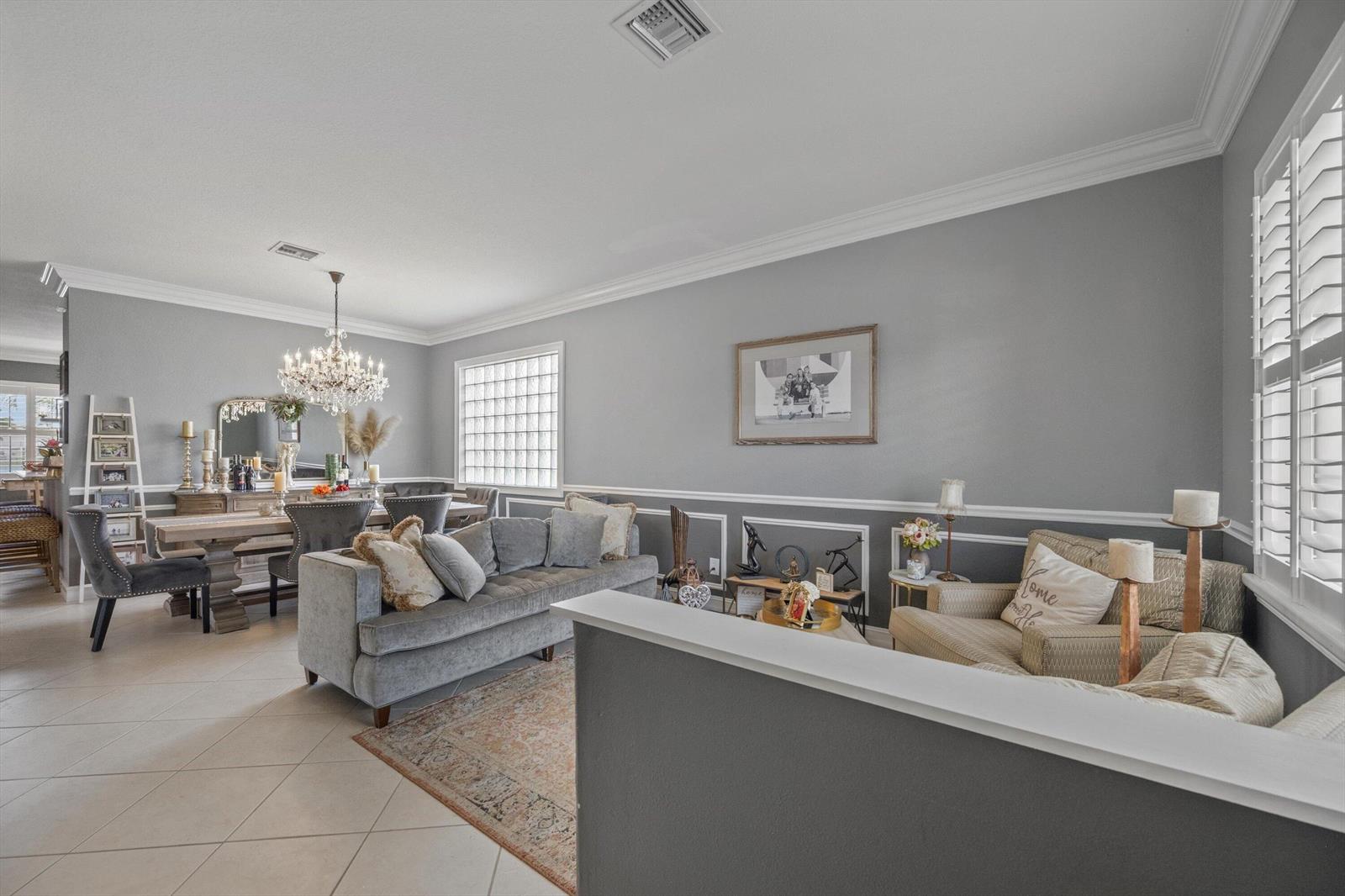 A living and dining area features gray walls, crown molding, tile flooring, and a chandelier — 11577 Ponywalk Trail, Boynton Beach FL 33473, BOYNTON BEACH, FL