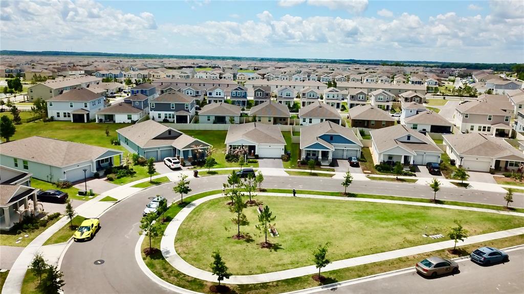 An aerial view shows a suburban neighborhood with houses, a central grassy island, and streets — 1578 CONTENTMENT LOOP, KISSIMMEE, FL