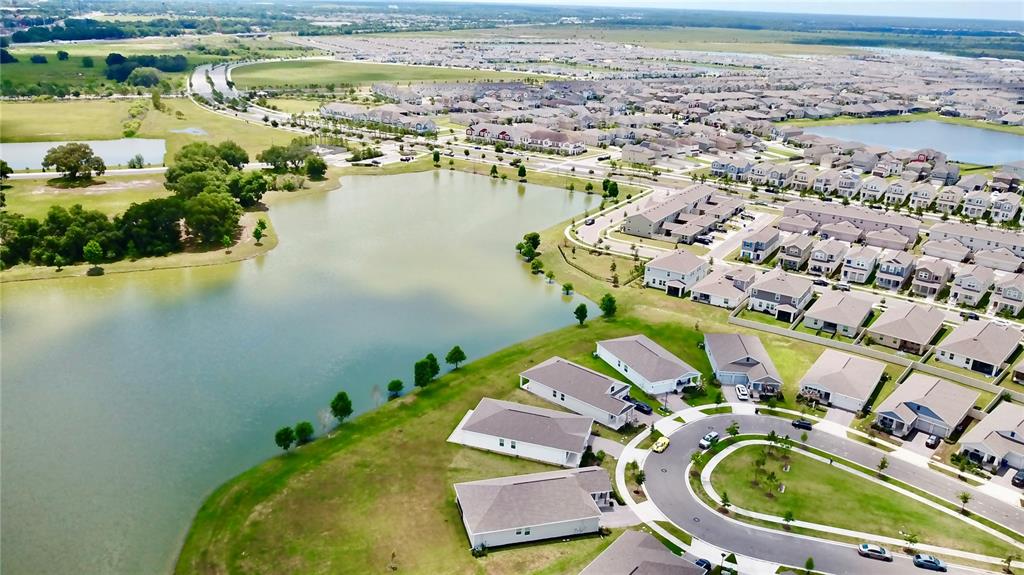 An aerial view shows a suburban neighborhood with houses situated along a large retention pond — 1578 CONTENTMENT LOOP, KISSIMMEE, FL