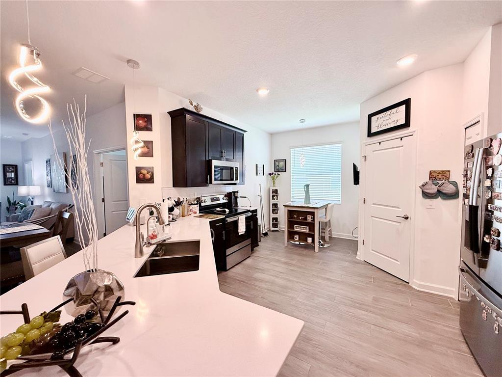 A kitchen features dark wood cabinets, a white quartz island, and light wood-look flooring — 1578 CONTENTMENT LOOP, KISSIMMEE, FL
