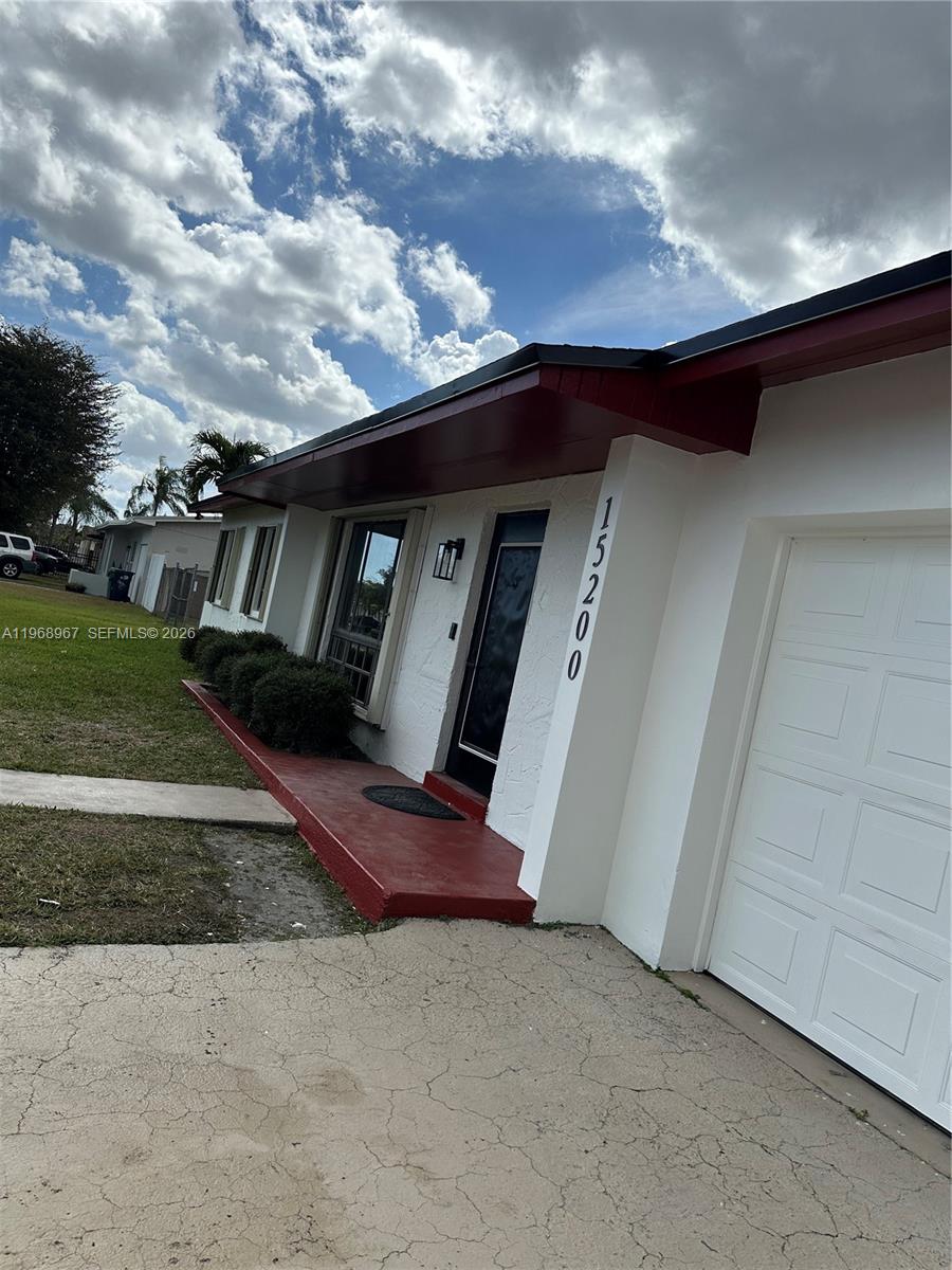 A white house exterior features a red porch, a dark front door, and a garage — 15200 SW 109 ave, Miami FL 33157, MIAMI, FL