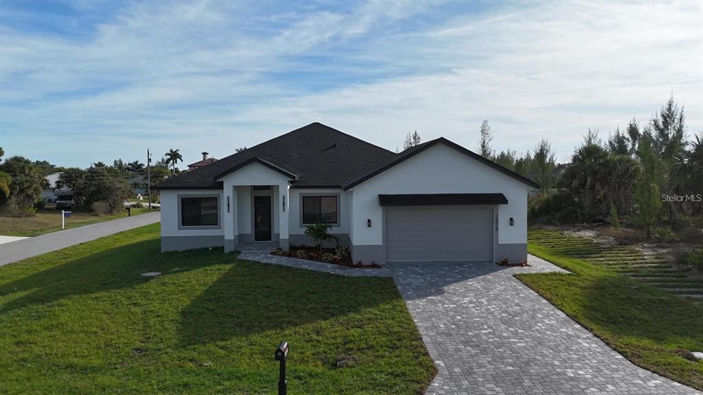 A single-story house with a white exterior, dark roof, and a paved driveway — 10426 LIVE OAK ROAD, PORT CHARLOTTE, FL