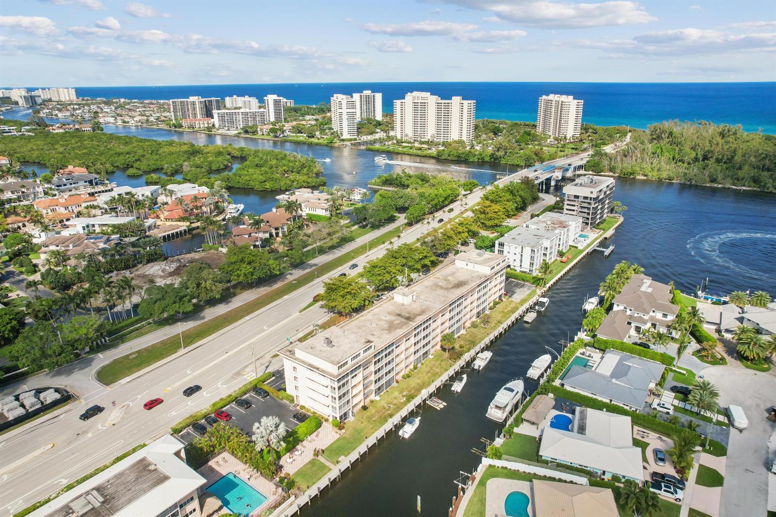 An aerial view shows a multi-story apartment building situated along a canal near the ocean — 750 NE Spanish River Boulevard # 103, Boca Raton FL 33431, BOCA RATON, FL