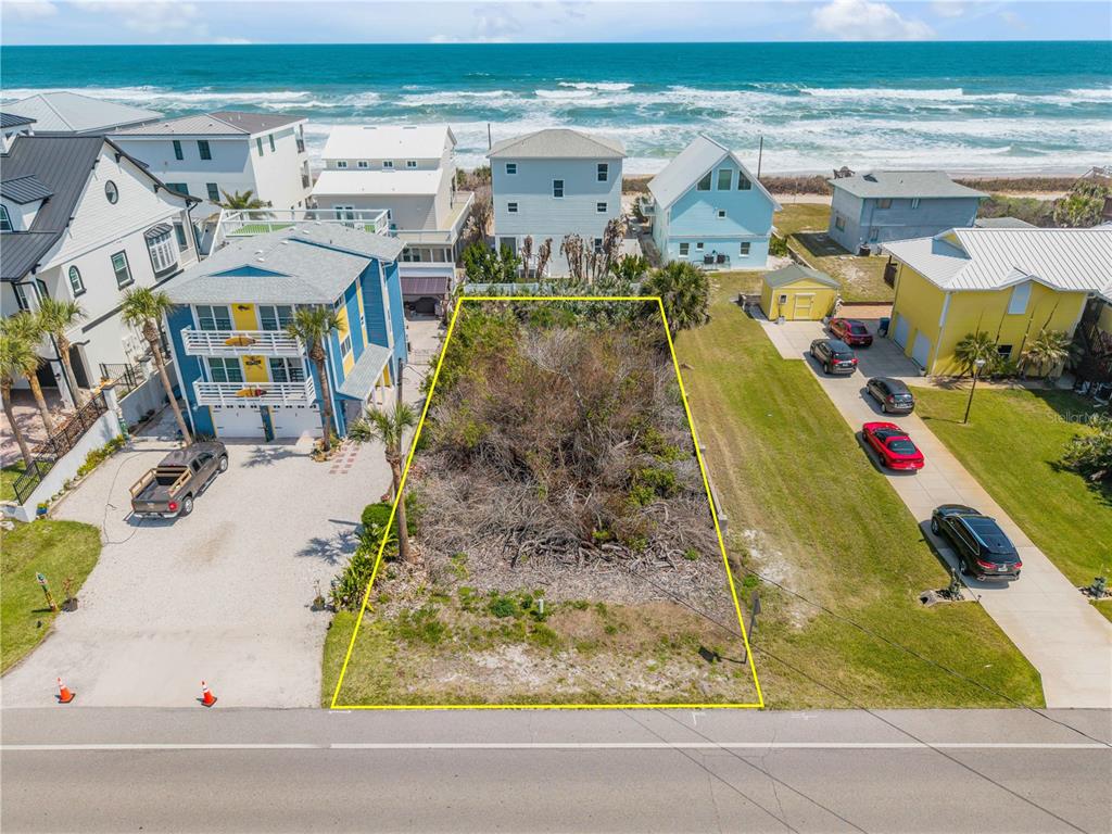 An aerial view shows a vacant, rectangular beachside lot situated between two residential houses — TURTLEMOUND ROAD, NEW SMYRNA BEACH, FL