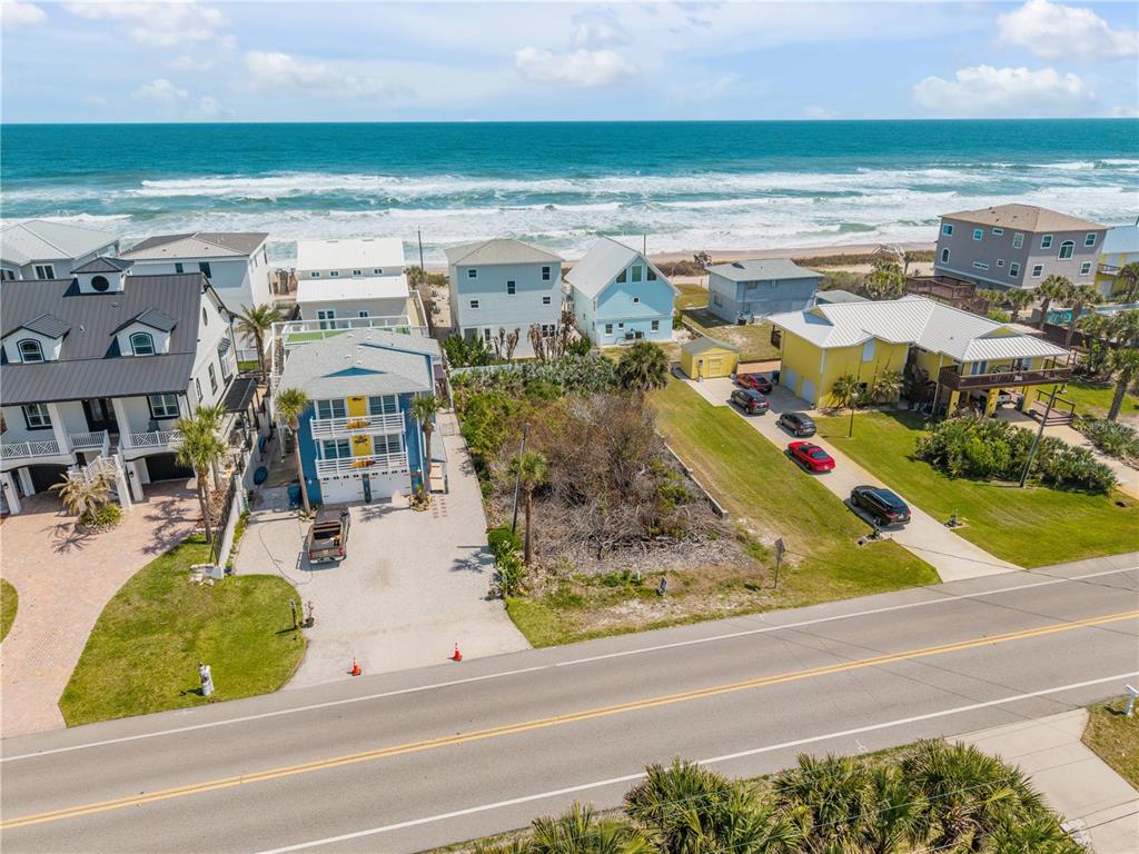 An aerial view shows a coastal neighborhood with houses, a vacant lot, and the ocean — TURTLEMOUND ROAD, NEW SMYRNA BEACH, FL