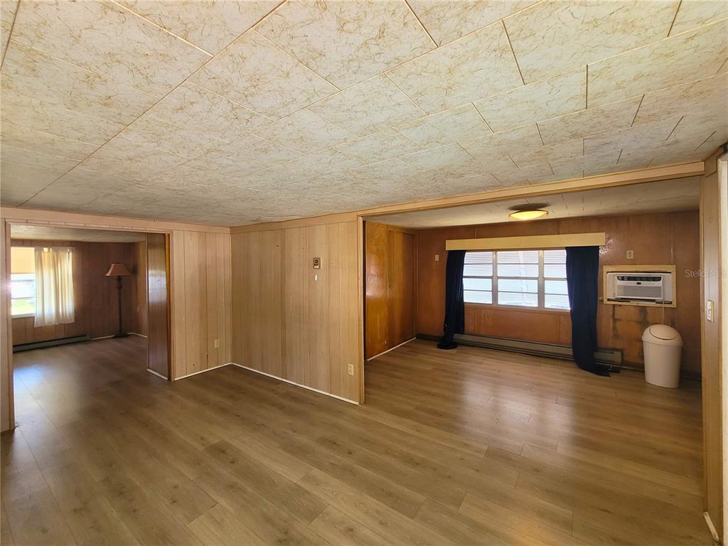 A living area with wood-look flooring, wood paneling, and a drop ceiling — 522 49TH AVENUE W, BRADENTON, FL