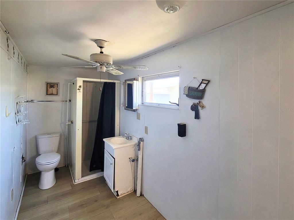 A bathroom features a toilet, a shower stall, a vanity sink, and light-colored wood flooring — 522 49TH AVENUE W, BRADENTON, FL