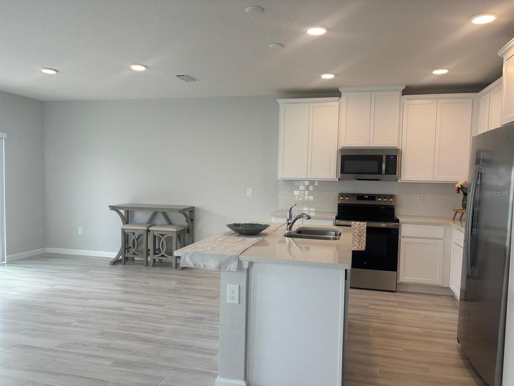 A kitchen with white cabinets, stainless steel appliances, and a central island with a sink — 4616 CAMPSITE, ORLANDO, FL