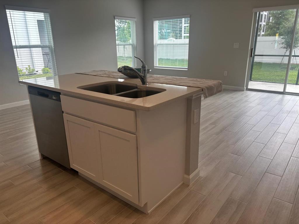 A kitchen island with a stainless steel sink and dishwasher sits on light wood-look flooring — 4616 CAMPSITE, ORLANDO, FL