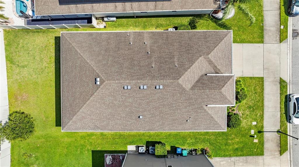 An aerial view shows the shingled roof of a house surrounded by a grassy lawn — 12216 PRAIRIE PLANTATION WAY, ORLANDO, FL