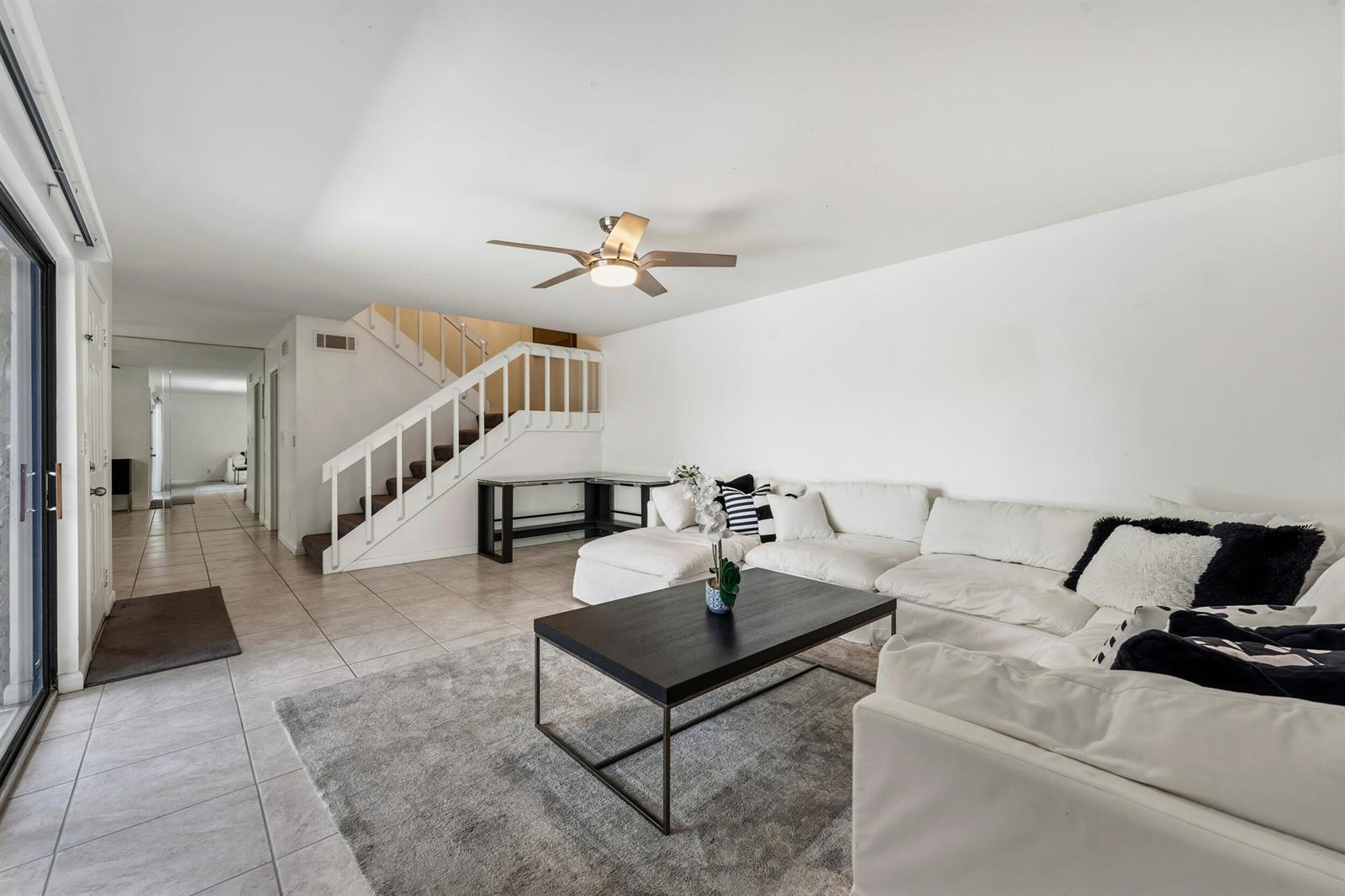 A living room features a white sectional sofa, a dark coffee table, and a staircase — 3852 SE Jefferson Street, Stuart FL 34997, STUART, FL