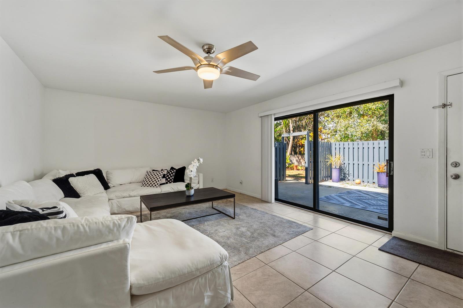 A living room features a white sectional sofa, a coffee table, and a sliding glass door — 3852 SE Jefferson Street, Stuart FL 34997, STUART, FL
