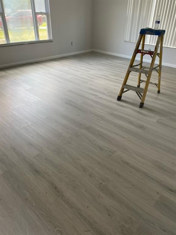 An empty room features light-colored wood-look flooring, gray walls, a window, and a stepladder — 478 WATER PLACE, OCALA, FL