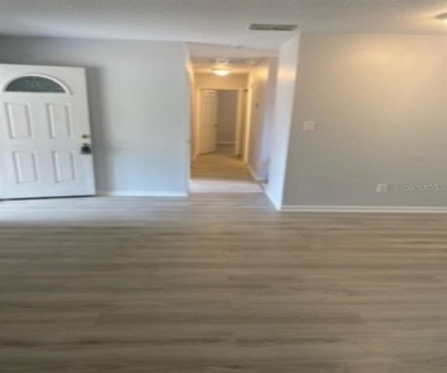 An interior view shows a living area with light wood-look flooring and a front door — 478 WATER PLACE, OCALA, FL