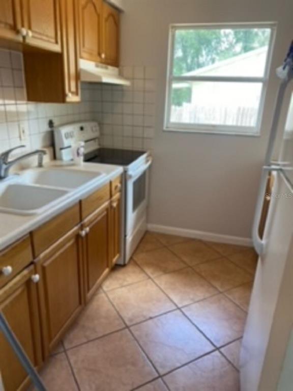 A kitchen features wood cabinets, a white sink, a stove, and tiled flooring — 478 WATER PLACE, OCALA, FL