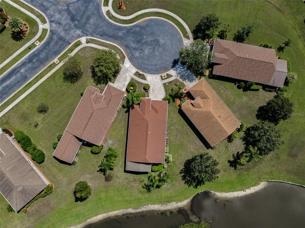 An aerial view shows four houses with brown roofs situated around a cul-de-sac near water — 12021 FERN TERRACE COURT, TRINITY, FL