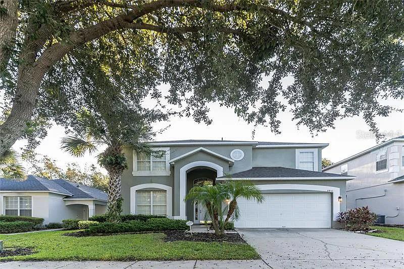 A two-story house with a gray exterior, a two-car garage, and a large front tree — 8452 SECRET KEY COVE, KISSIMMEE, FL
