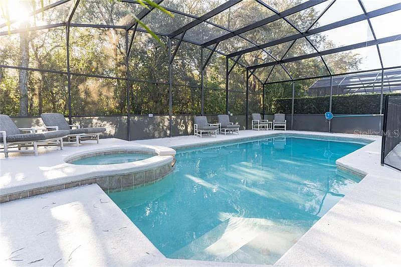 A screened-in swimming pool and spa area with lounge chairs on a concrete deck — 8452 SECRET KEY COVE, KISSIMMEE, FL