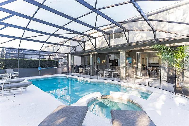 A screened-in patio features a swimming pool, a hot tub, and outdoor lounge furniture — 8452 SECRET KEY COVE, KISSIMMEE, FL