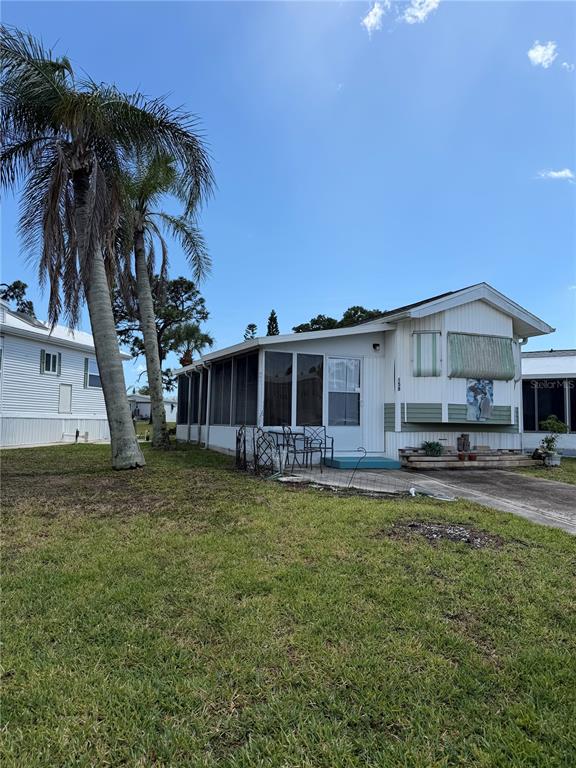 A single-story manufactured home with a screened-in porch and a palm tree in the yard — 158 BROOKSHIRE DRIVE, NOKOMIS, FL
