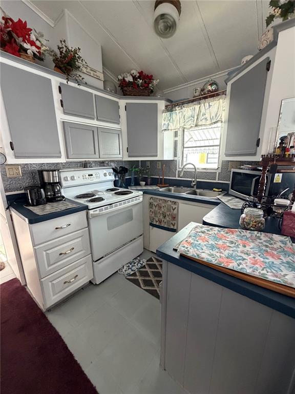 A kitchen features gray cabinets, white appliances, a patterned backsplash, and a blue countertop — 158 BROOKSHIRE DRIVE, NOKOMIS, FL
