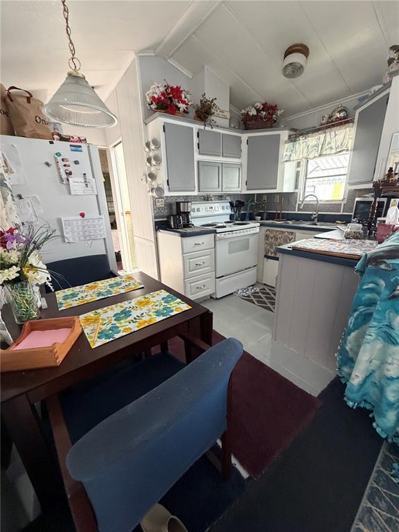 A kitchen with white cabinets, a dining table, and a white stove in a home — 158 BROOKSHIRE DRIVE, NOKOMIS, FL