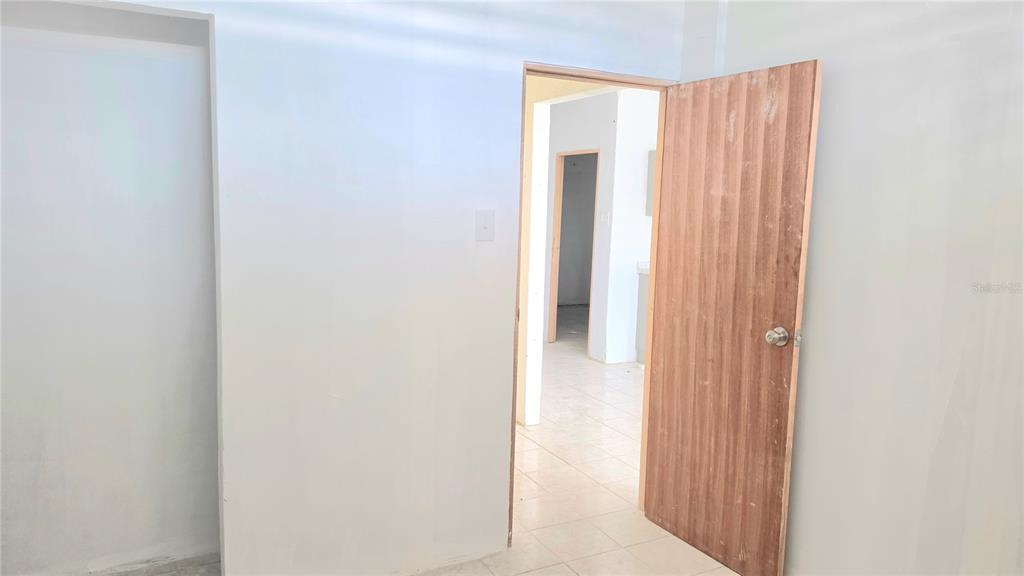 An interior view shows a white room with a wooden door leading to another space — Bloque AB  5 CALLE JULIO ANDINO, SAN JUAN, PR