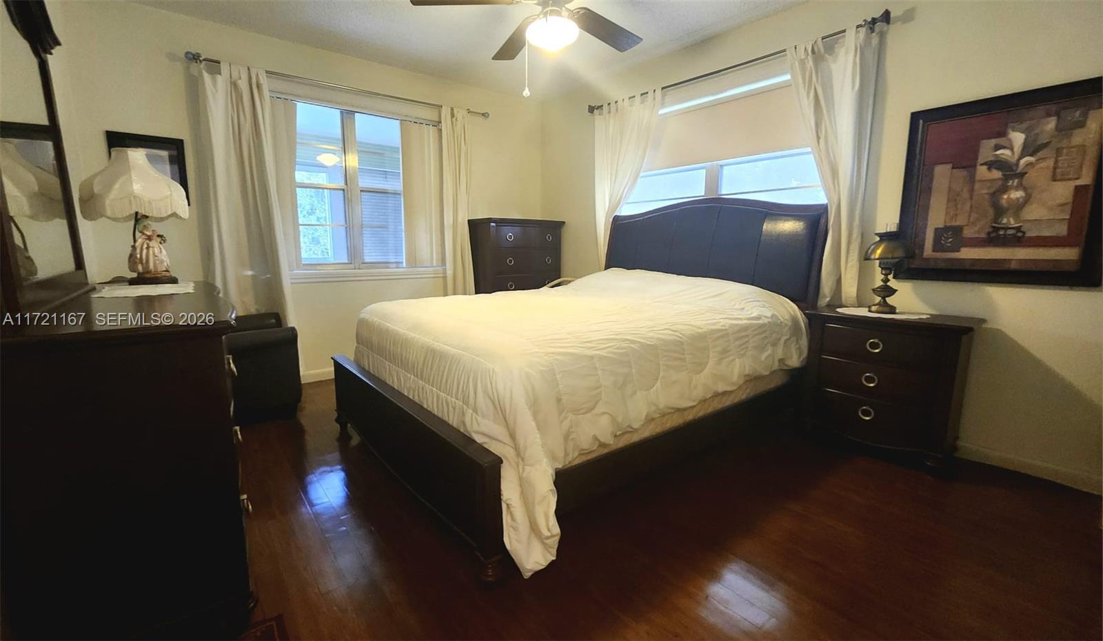 A bedroom features a dark wood bed frame, matching nightstand, and hardwood floors — 564 Durham T # 564, Deerfield Beach FL 33442, DEERFIELD BEACH, FL