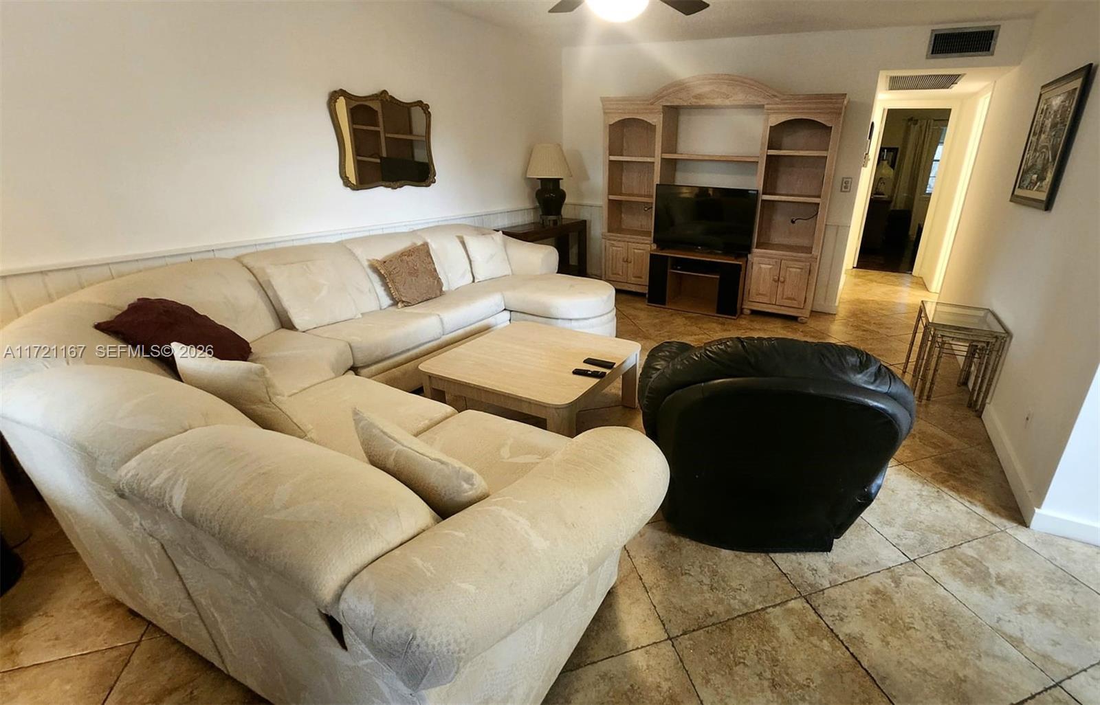 A living room features a large beige sectional sofa, a black armchair, and a wooden entertainment center — 564 Durham T # 564, Deerfield Beach FL 33442, DEERFIELD BEACH, FL