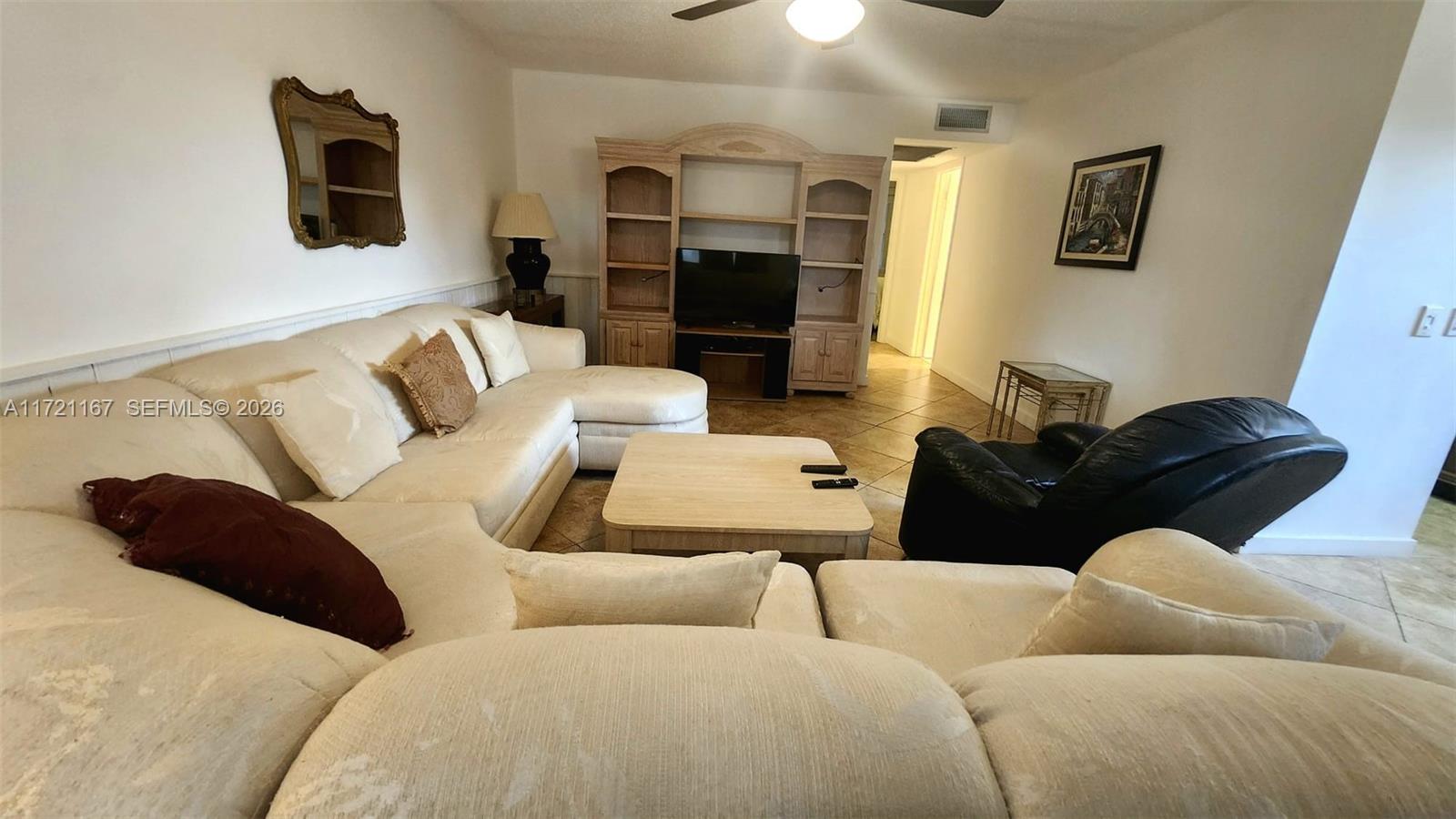 A living room features a large beige sectional sofa, a wooden entertainment center, and tile flooring — 564 Durham T # 564, Deerfield Beach FL 33442, DEERFIELD BEACH, FL