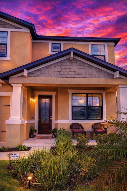 A two-story house exterior features a covered front porch, a dark door, and sunset sky — 1216 OLD WINDSOR WAY, SPRING HILL, FL