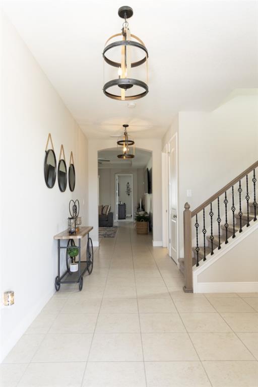 A tiled entryway features a console table, wall mirrors, pendant lighting, and a carpeted staircase — 1216 OLD WINDSOR WAY, SPRING HILL, FL