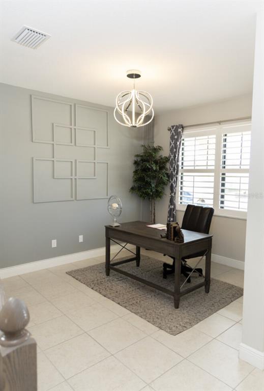 A home office features a dark wood desk, geometric wall molding, and a modern light fixture — 1216 OLD WINDSOR WAY, SPRING HILL, FL