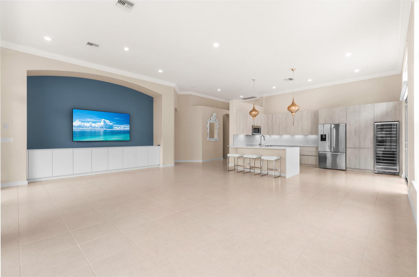 An open-concept living room and kitchen featuring a blue accent wall, cabinetry, and tile flooring — 7916 Montecito Place, Delray Beach FL 33446, DELRAY BEACH, FL